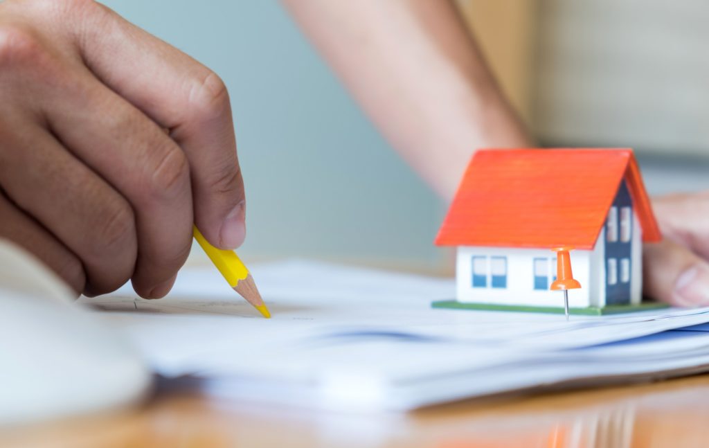Close-up architects are designing the house,model house place on house plan on the desk.