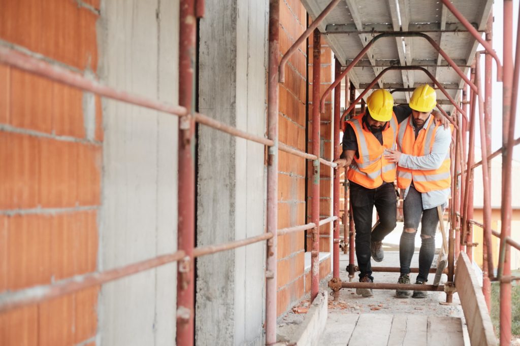 Manual Worker Helping Injured Colleague In Construction Site